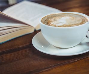 Close-up of cappuccino and book on table in cafeteria