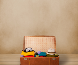 Retro tourist luggage with colorful clothes and copyspace on grungy ba
