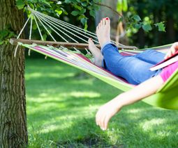 Young lady resting on hammock with book summer